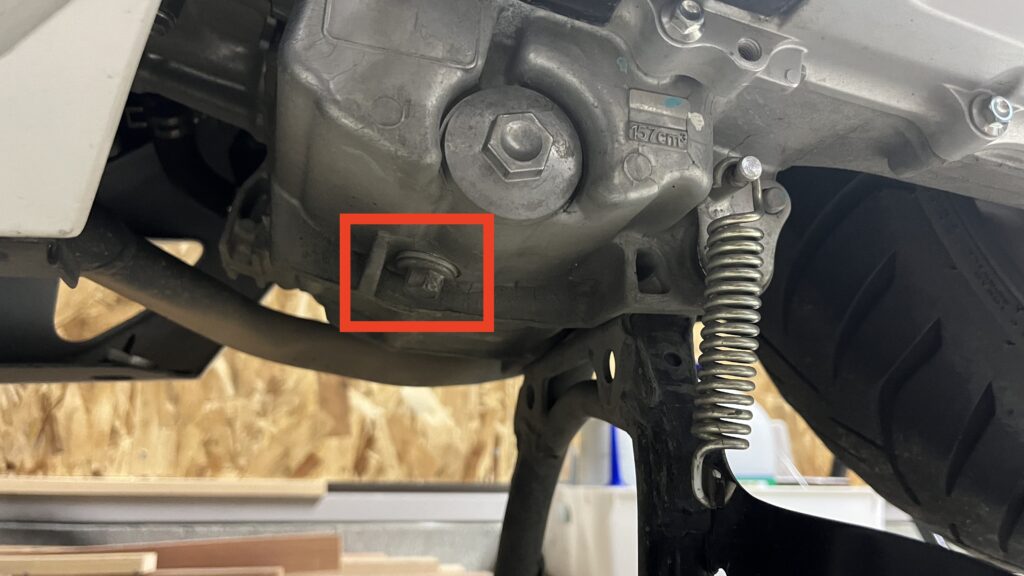 PCX160のオイル交換で外すドレンボルトの位置を赤枠で示した画像(車体下側から撮影)
