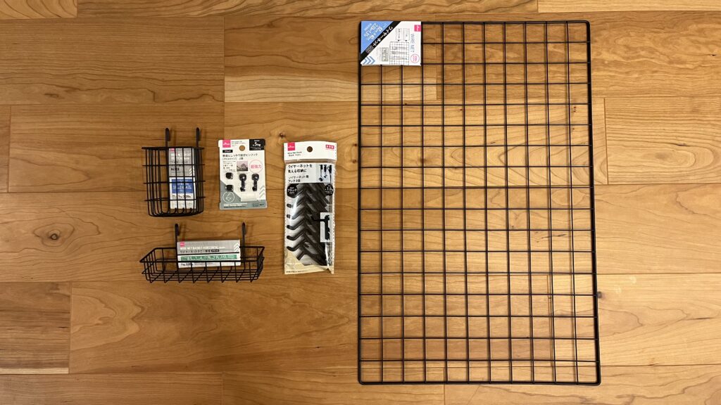 ダイソーで購入したワイヤーネットやフック、収納カゴなど壁掛け収納用アイテム一式を床に並べた様子
