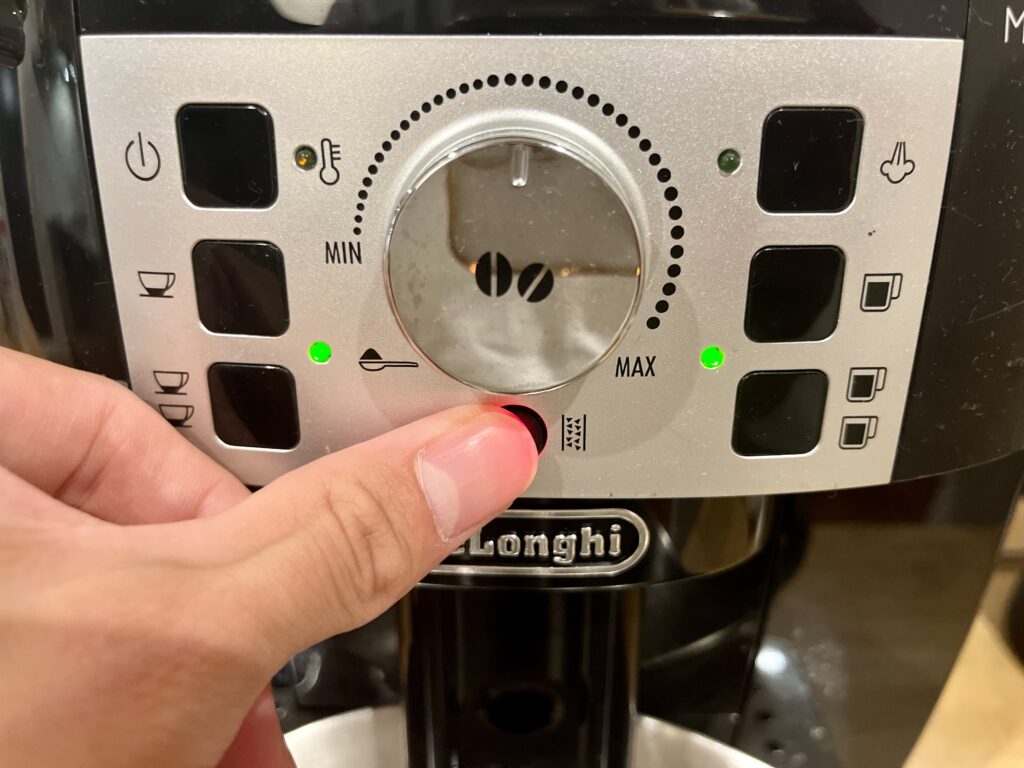 デロンギ マグニフィカSの除石灰ボタンを3秒長押ししている手元
