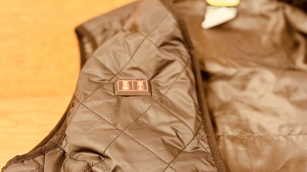 WIZ’A電熱ベストの胸元にある電源スイッチ。3秒長押しでオン・オフ、連続押しで温度切り替えができる操作ボタン。