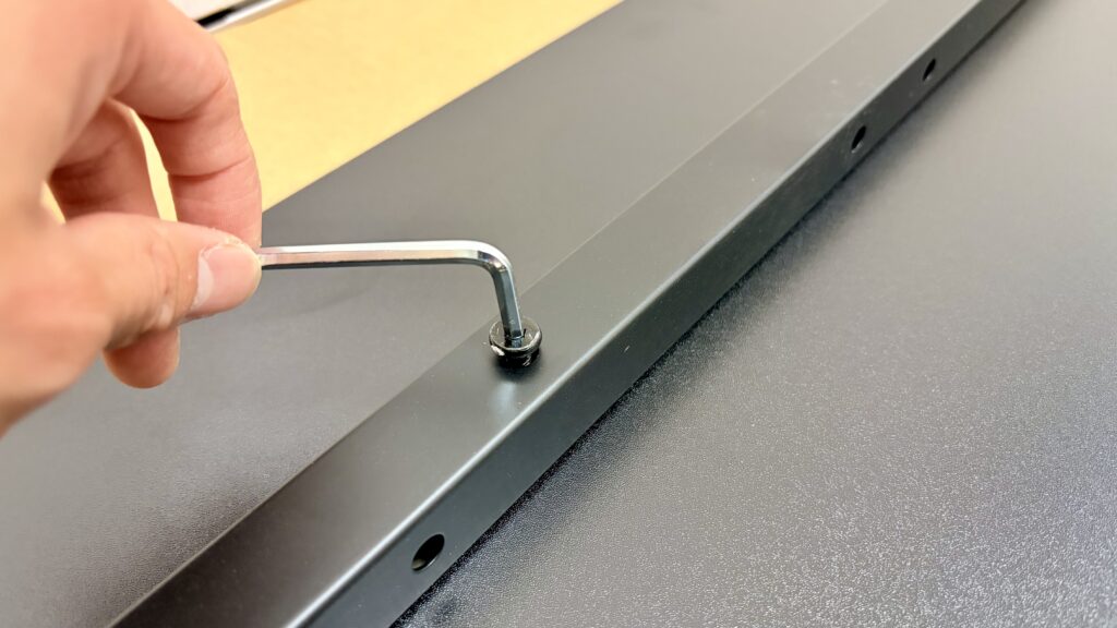 サンワダイレクトのPCデスクを六角レンチで組み立てている様子
