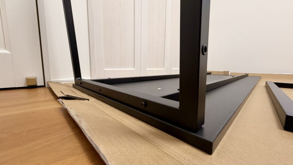 PCデスクのフレームを組み立て途中の状態で安定性を確認している様子
